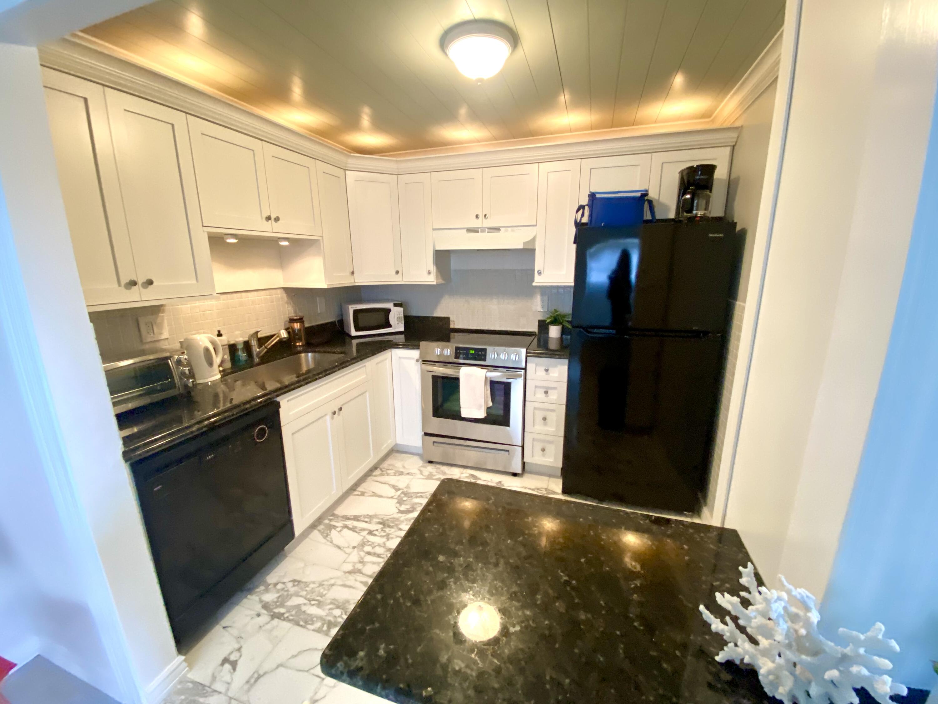 a kitchen with stainless steel appliances granite countertop a refrigerator a stove and a sink