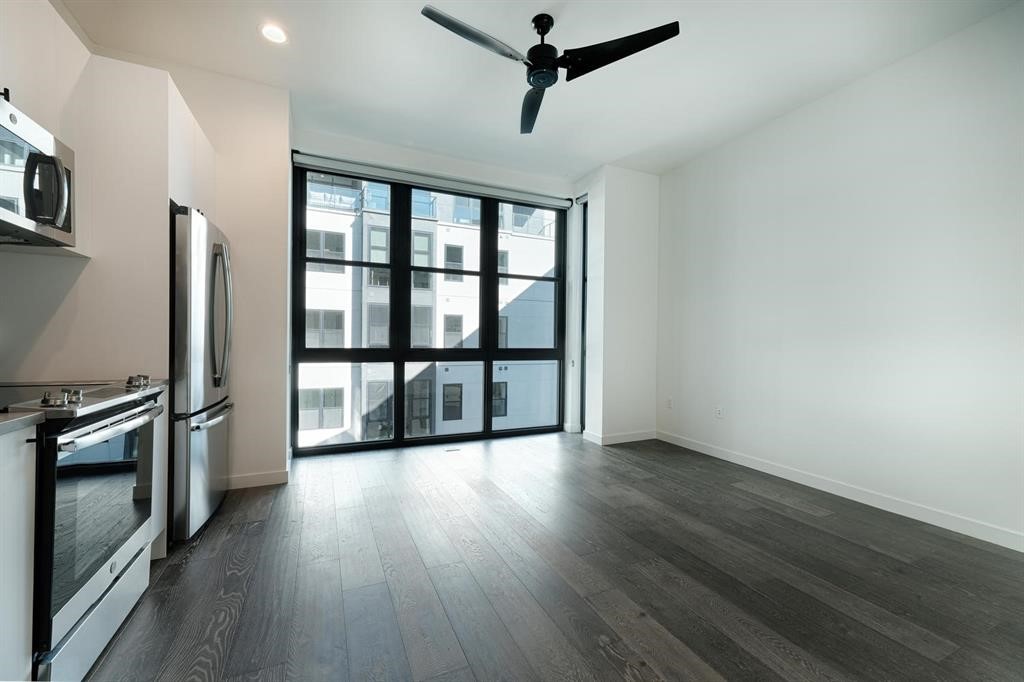 a view of a room with a large window wooden floor and a ceiling fan