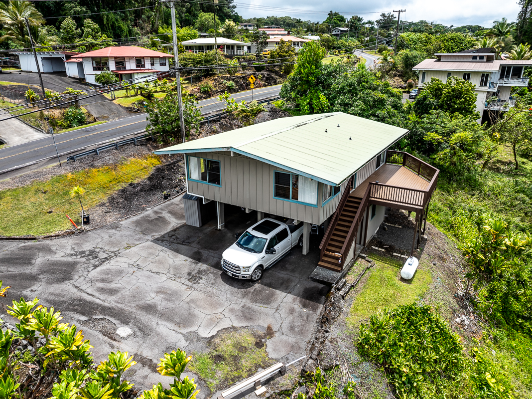 an aerial view of a house with swimming pool and large trees