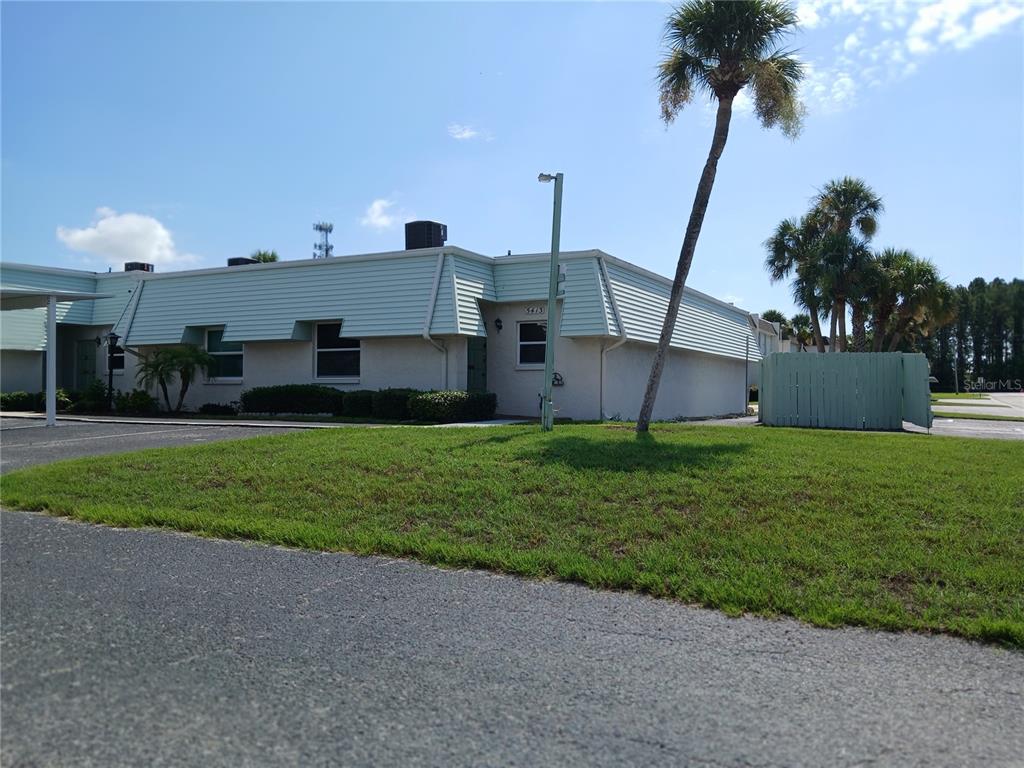 a view of a house with a yard and palm trees