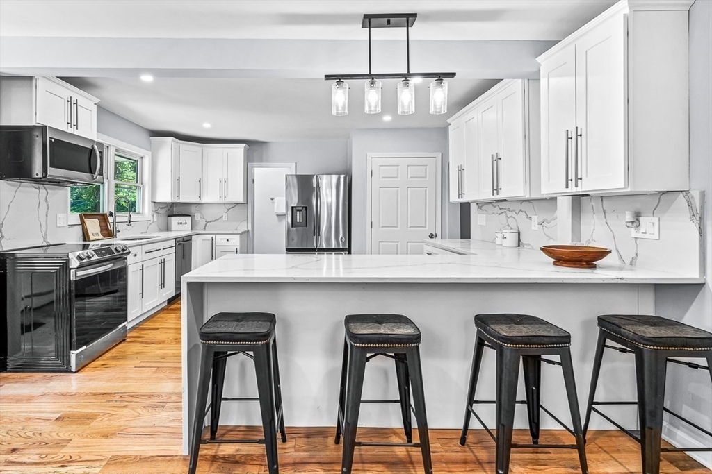 a kitchen with stainless steel appliances granite countertop a table chairs sink and cabinets