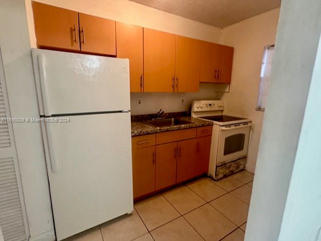 a white refrigerator freezer and a stove sitting inside of a kitchen