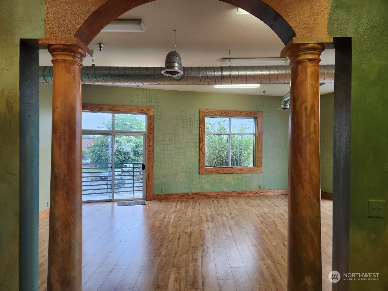 an empty room with wooden floor and windows