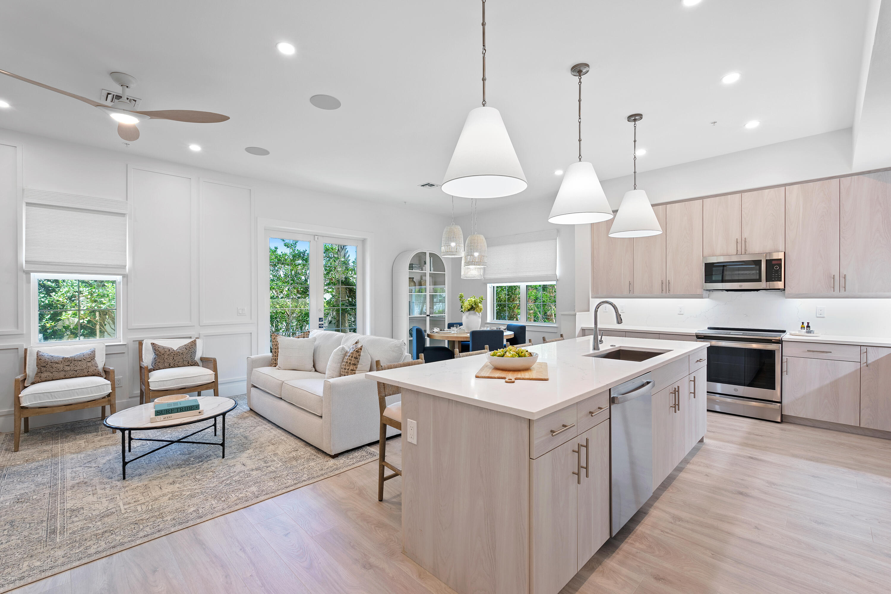 a large white kitchen with lots of counter space dining table and stainless steel appliances