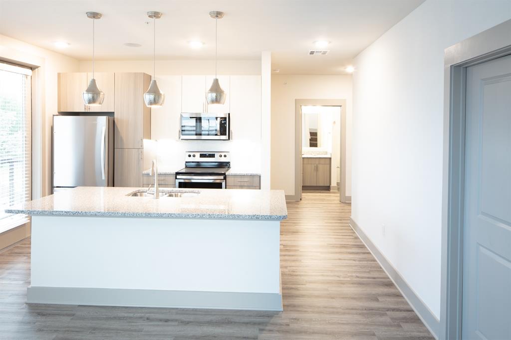 a view of a kitchen with kitchen island a counter top space a sink wooden floor and a refrigerator