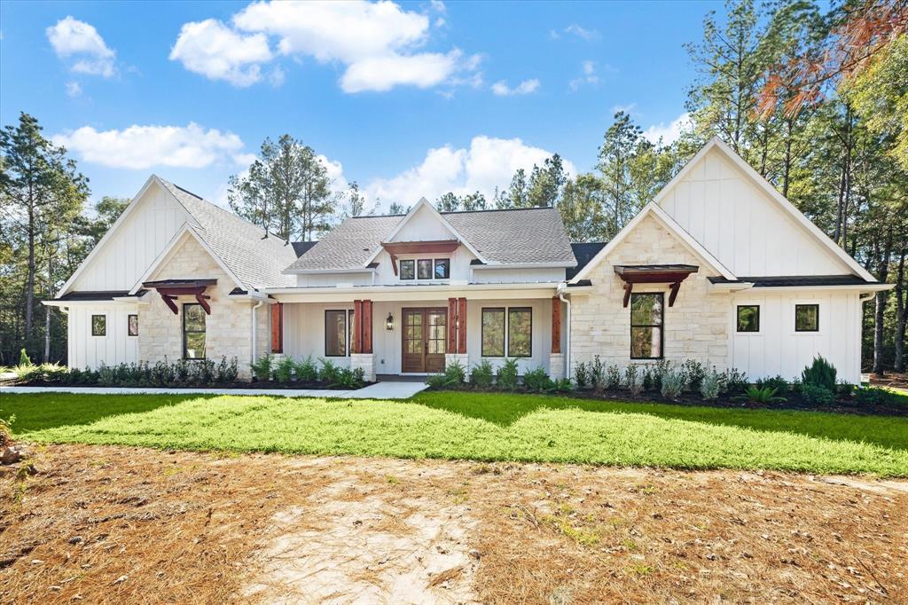 a view of a white house next to a yard with big trees