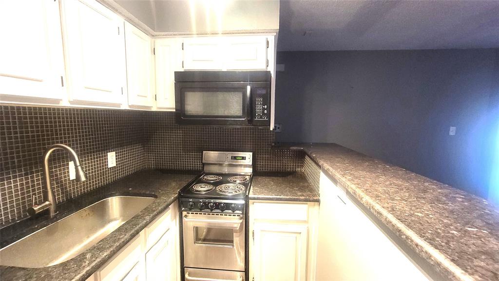 a kitchen with granite countertop a sink and a stove top oven