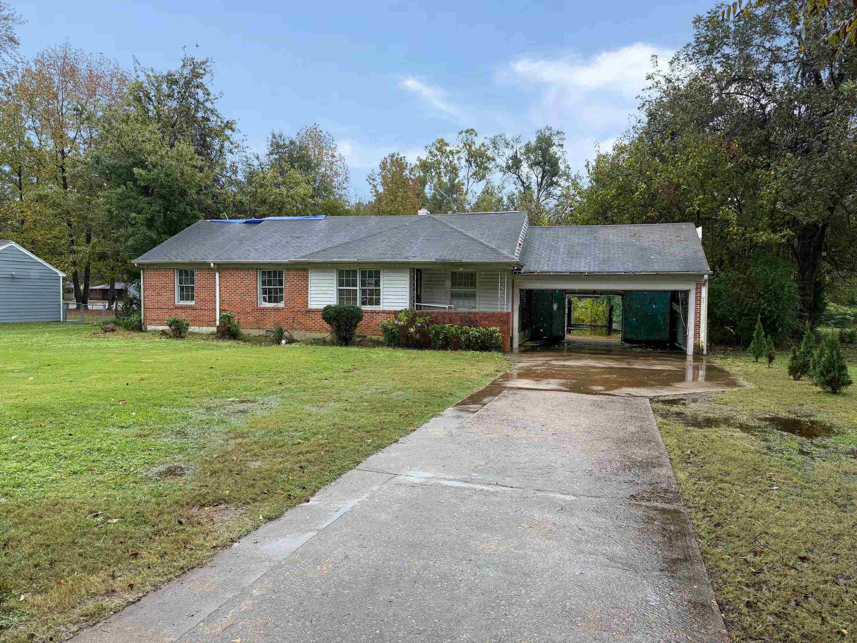 Ranch-style home featuring a front lawn and a carport