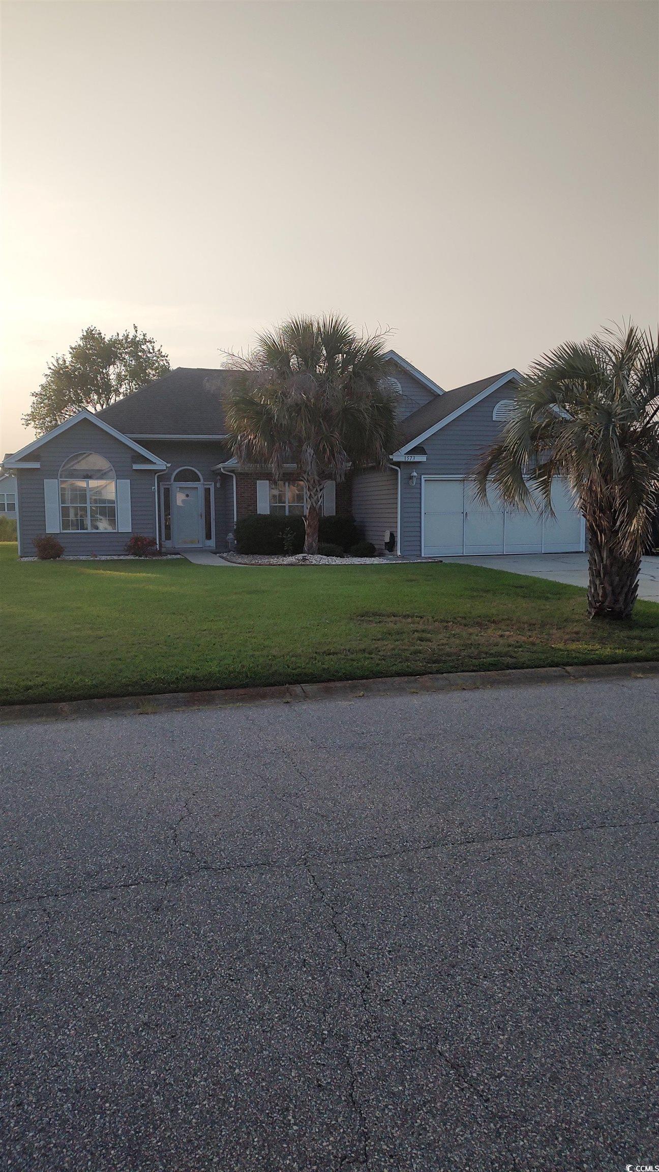 Single story home with a yard and a garage