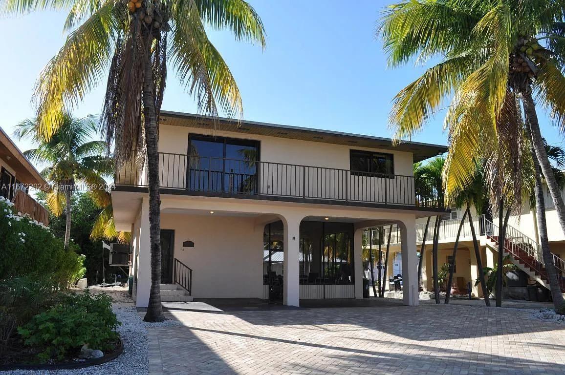 a view of a house with a yard and palm trees