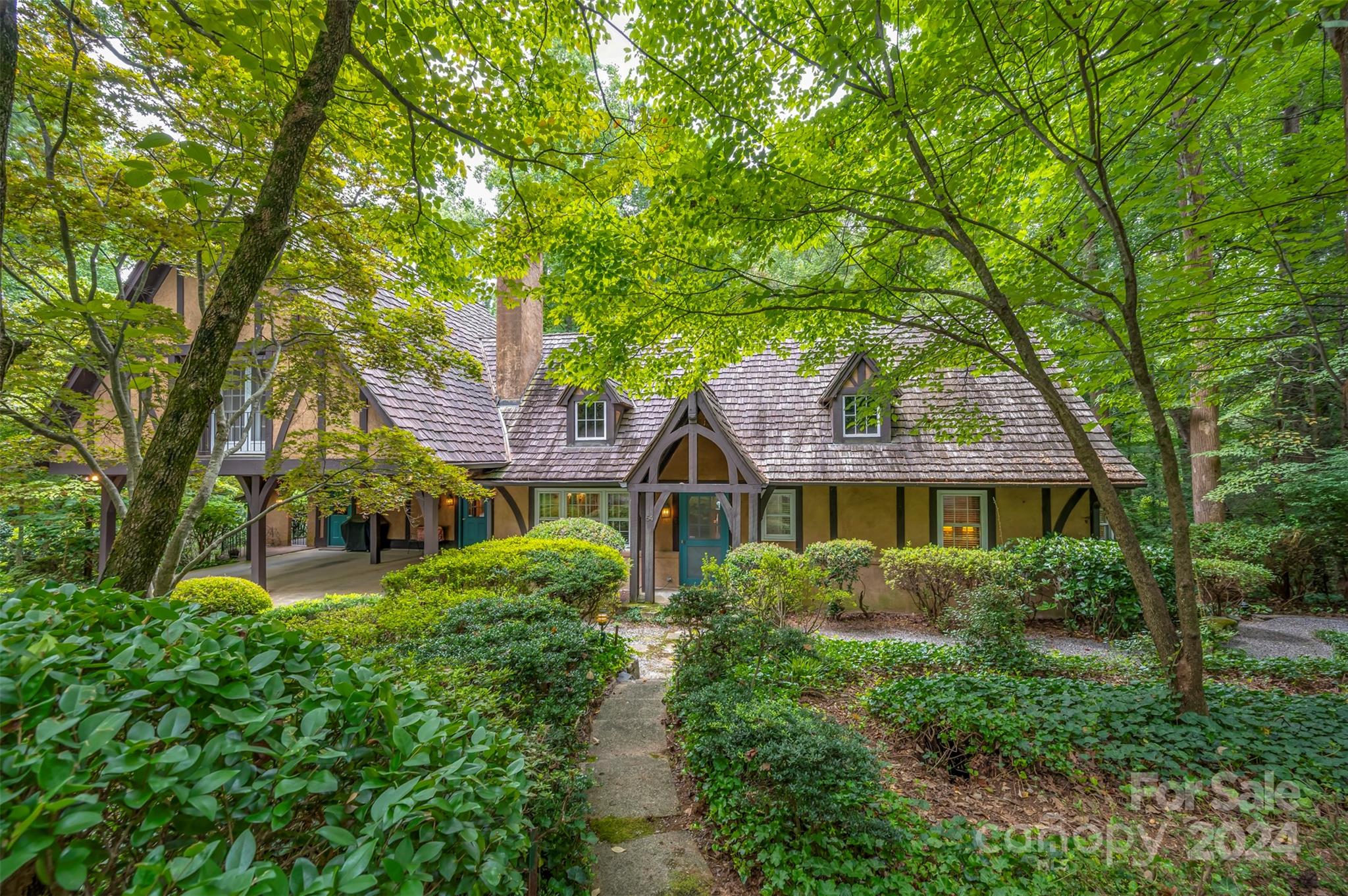 a view of house in front of a big yard with large trees