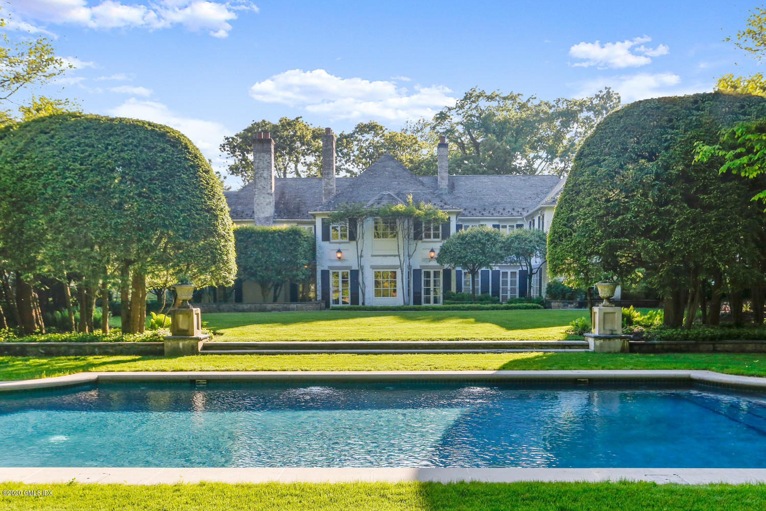 a view of swimming pool with lawn chairs and large trees