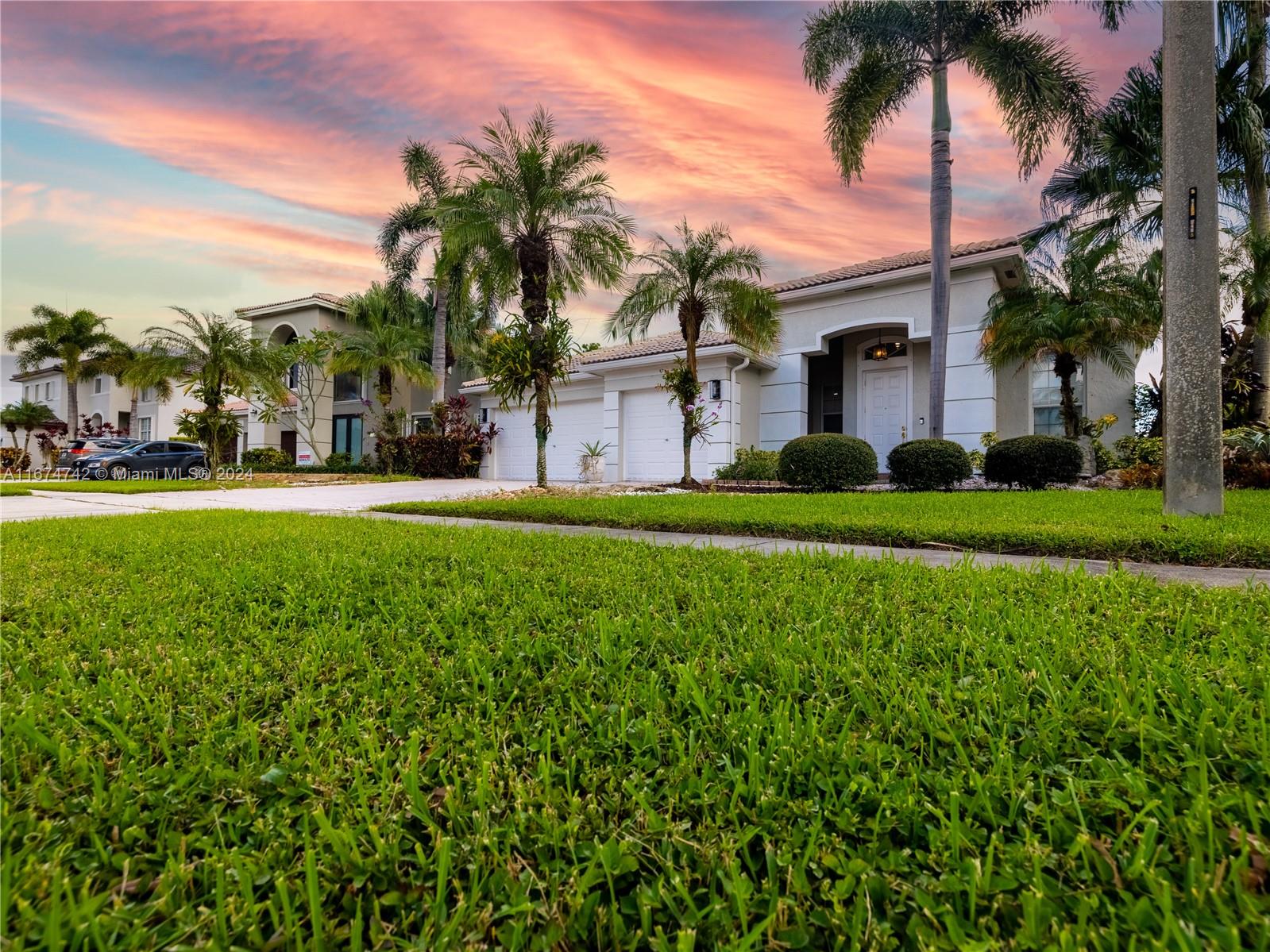 front view of a house with a yard and palm trees