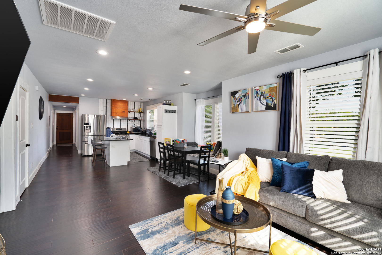 a living room with furniture kitchen view and a large window