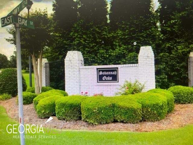 a sign of golf club on a wall under a tree