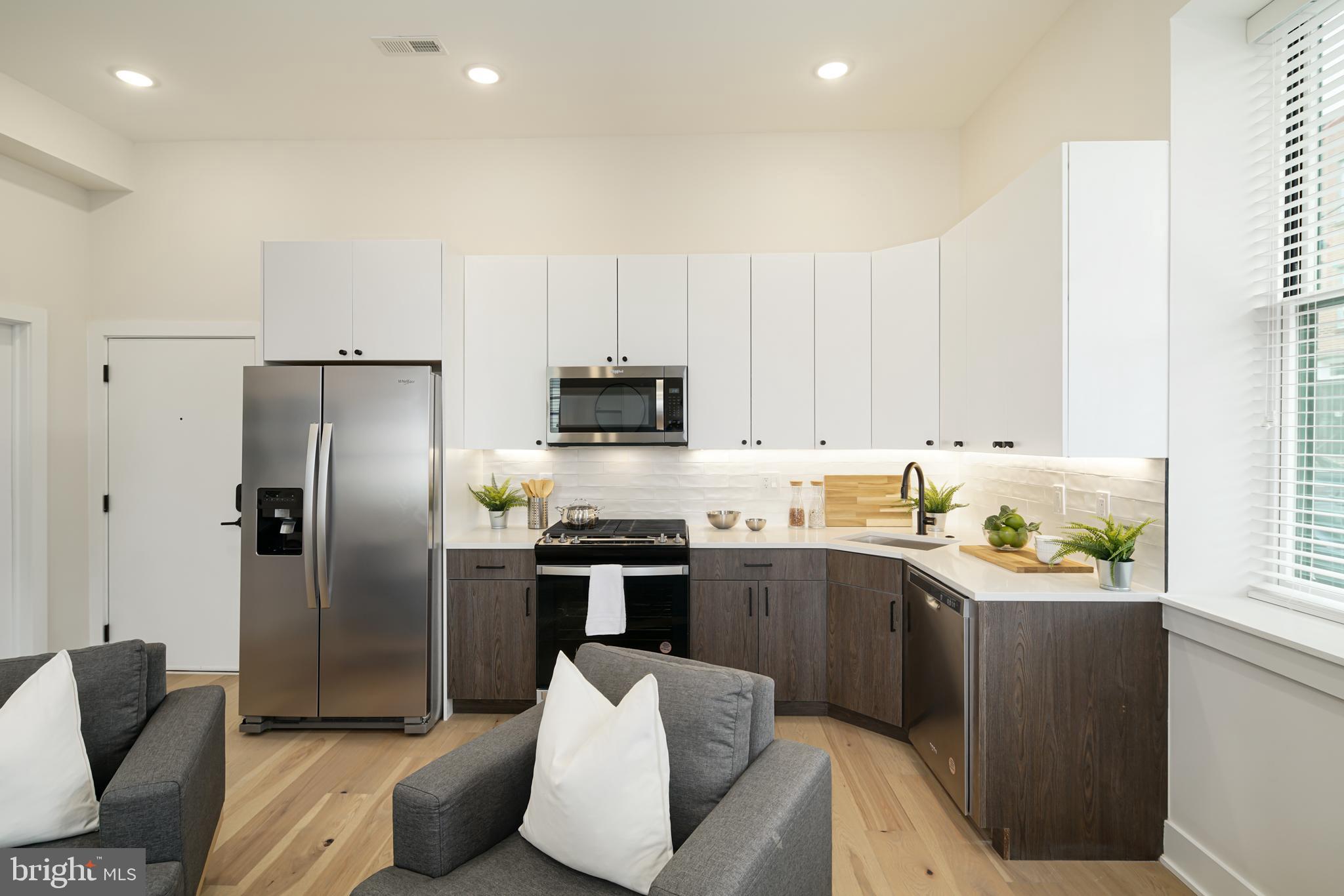 a kitchen with stainless steel appliances a sink a stove a refrigerator cabinets and a window