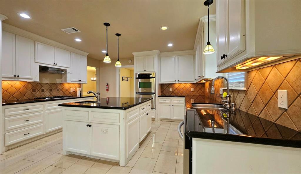 a kitchen with white cabinets and sink