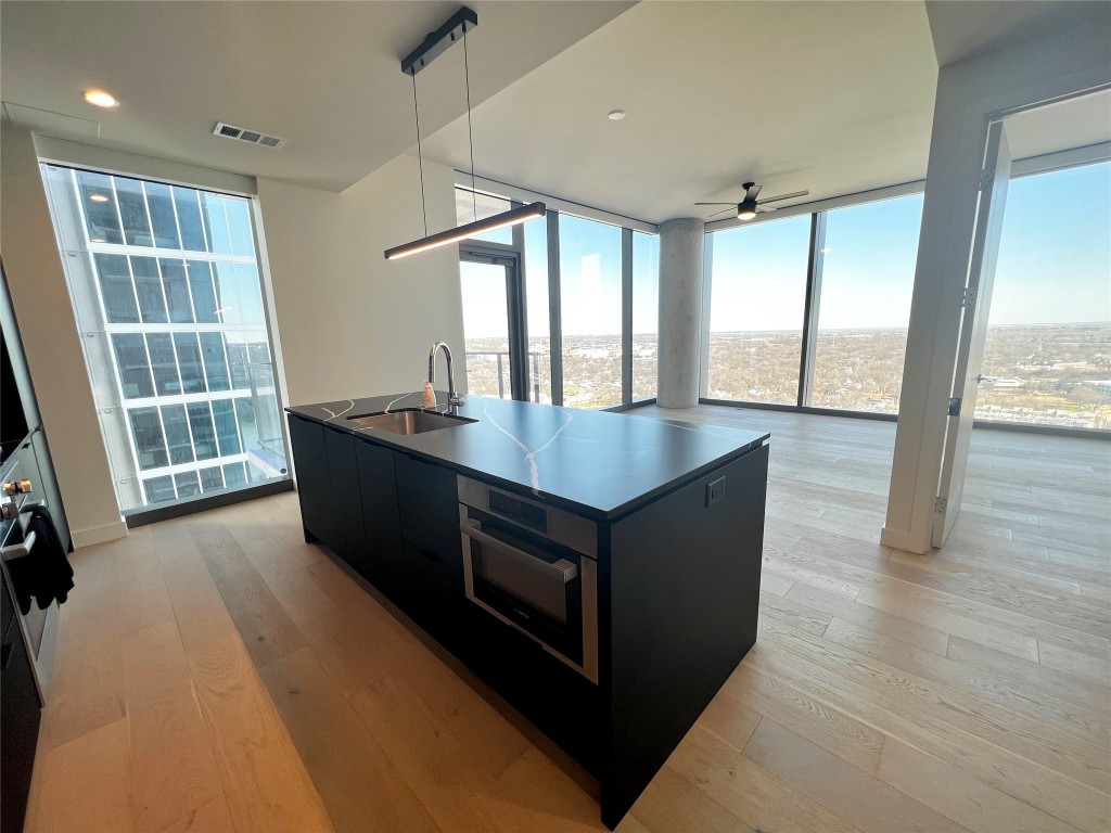 a kitchen with kitchen island a sink wooden floor and a large window