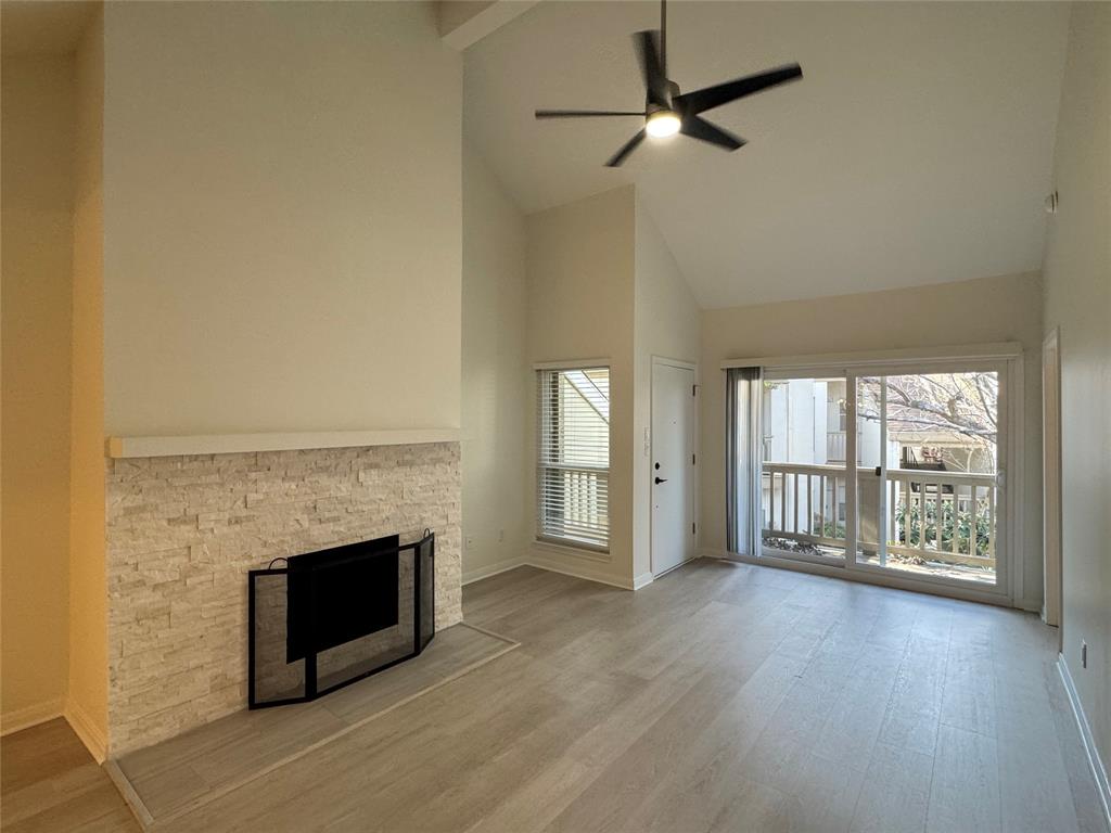 an empty room with wooden floor fireplace and windows