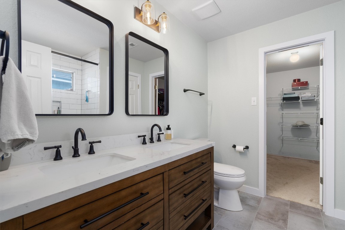 a bathroom with a toilet sink double vanity and mirror