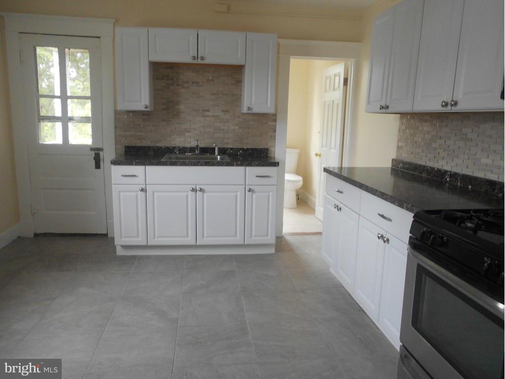 a kitchen with granite countertop white cabinets and white appliances