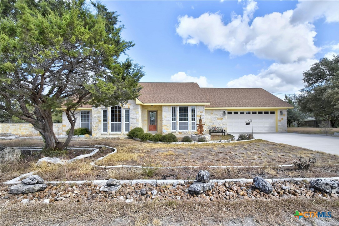 a front view of a house with a dirt yard and a large tree