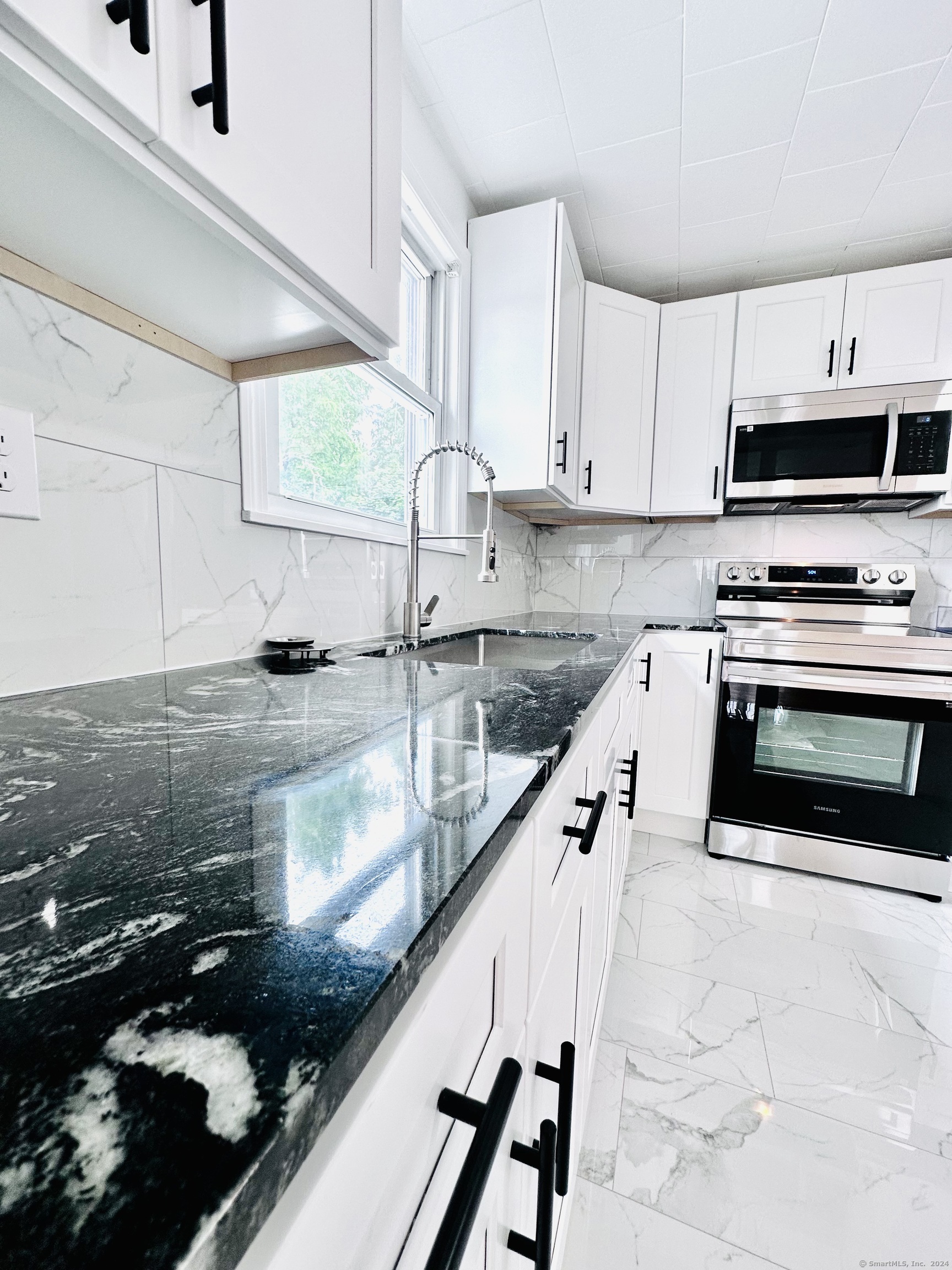 a kitchen with kitchen island granite countertop a sink a stove and a microwave