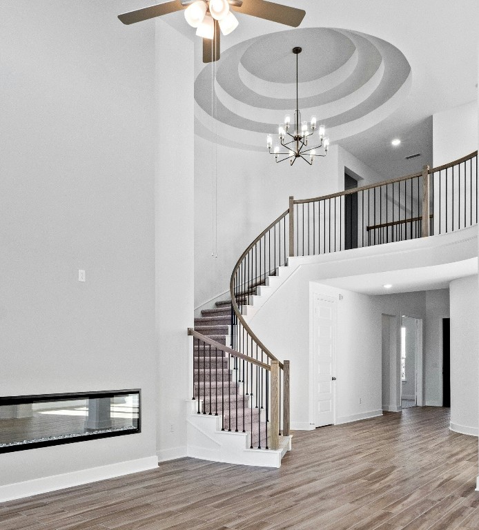 wooden floor with a chandelier fan and a rug