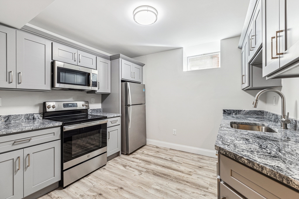 a kitchen with granite countertop wooden cabinets stainless steel appliances and a counter space