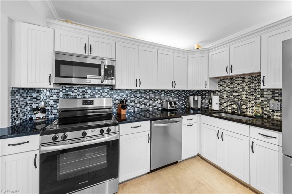 a kitchen with white cabinets and appliances