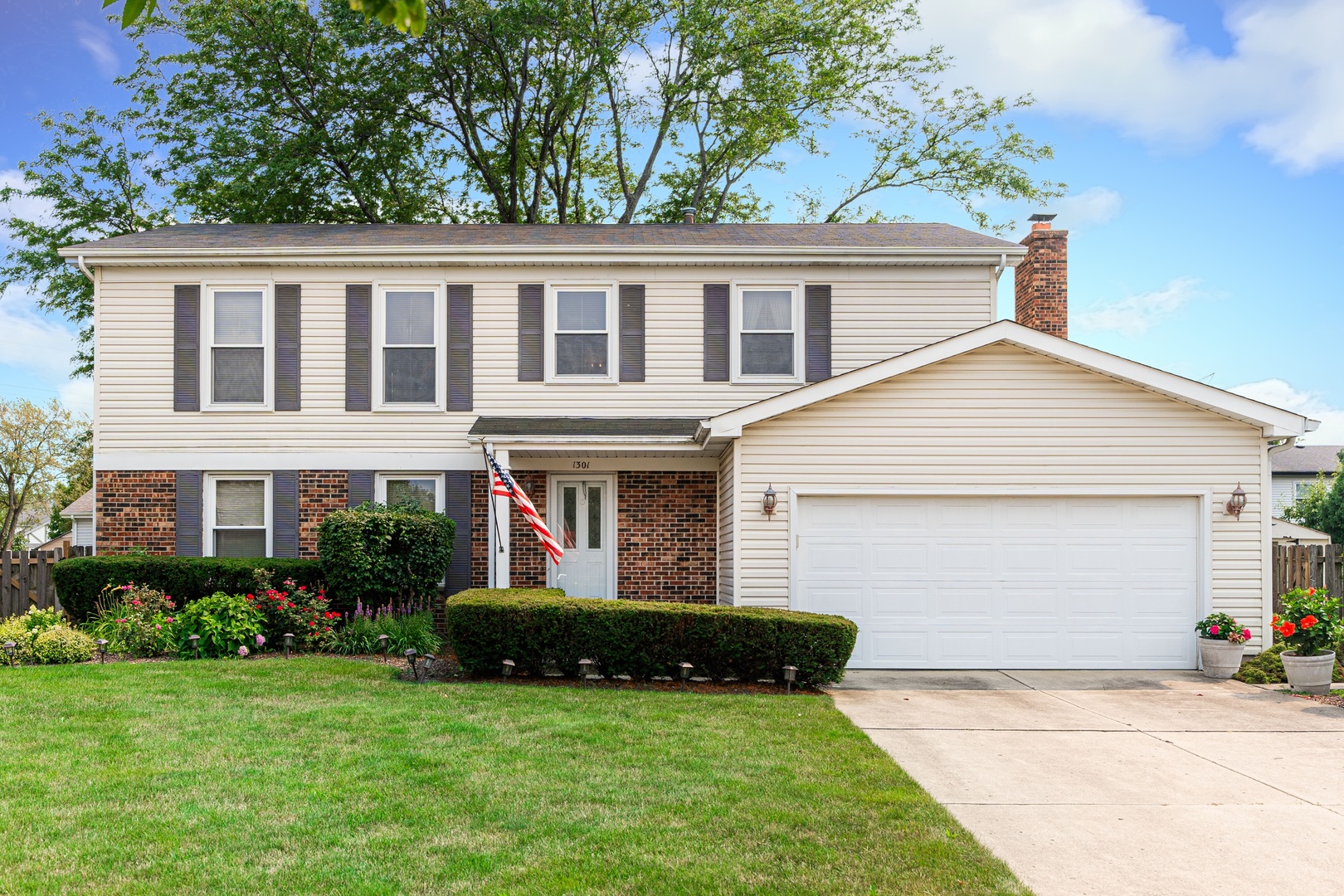 a view of a house with a yard plants and large tree