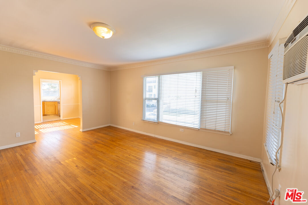 a view of an empty room with wooden floor and a window