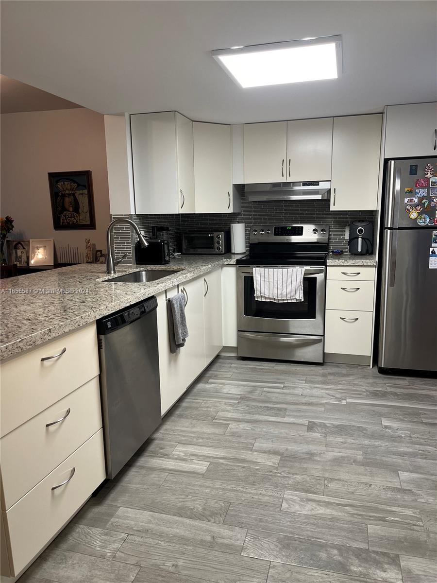 a kitchen with granite countertop a refrigerator and cabinets