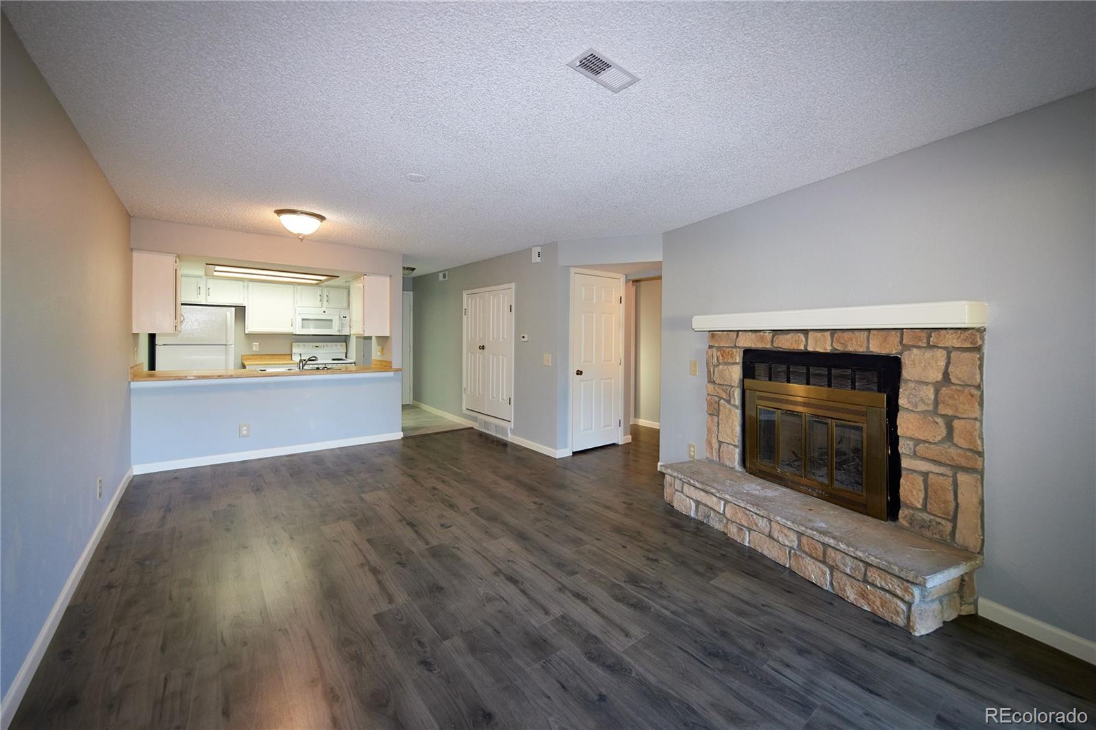 an empty room with wooden floor fireplace and window