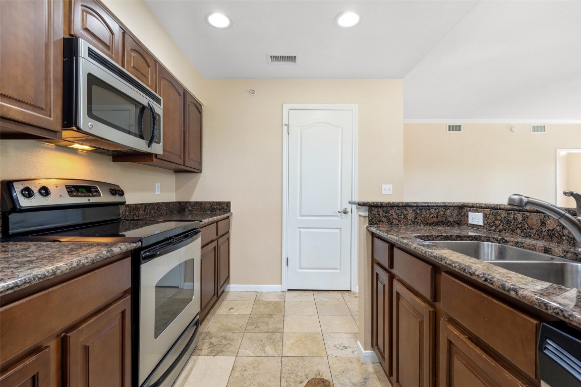 a kitchen with stainless steel appliances granite countertop a sink and a stove