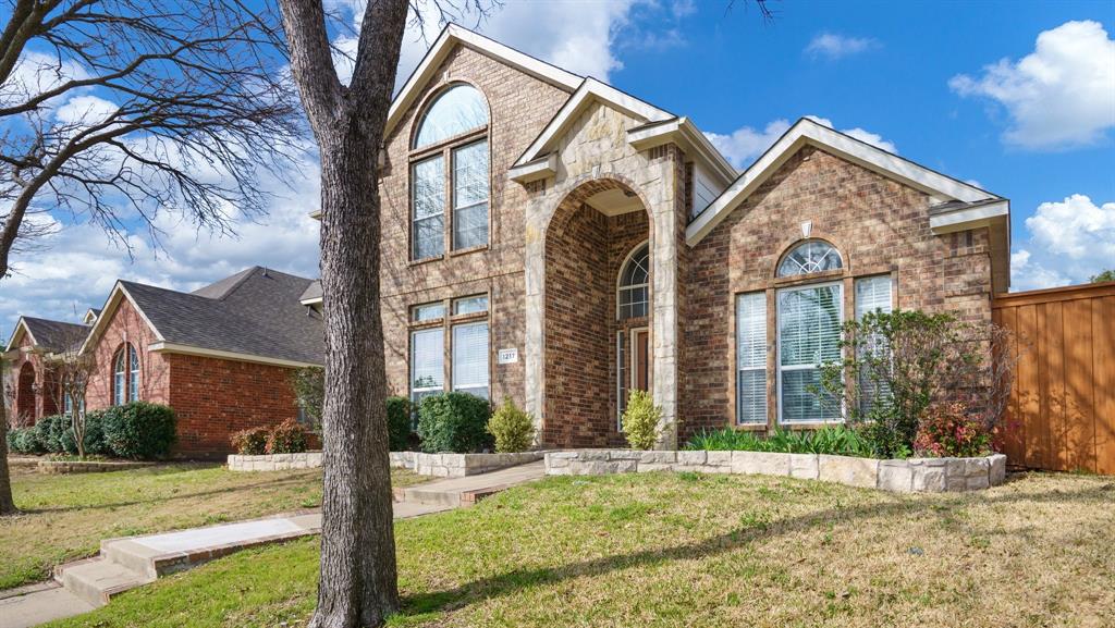 a view of a brick house with many windows and a yard