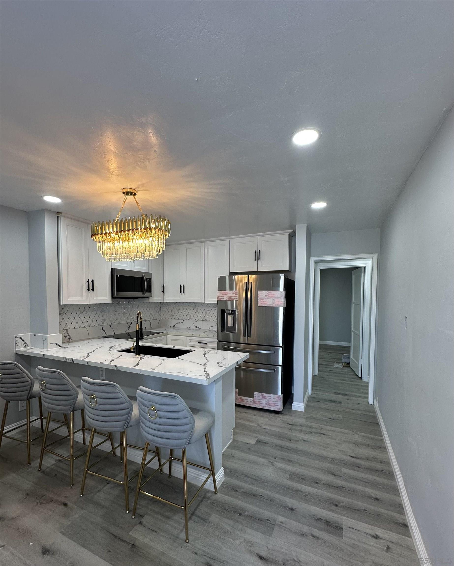 a kitchen with kitchen island granite countertop a sink and a refrigerator