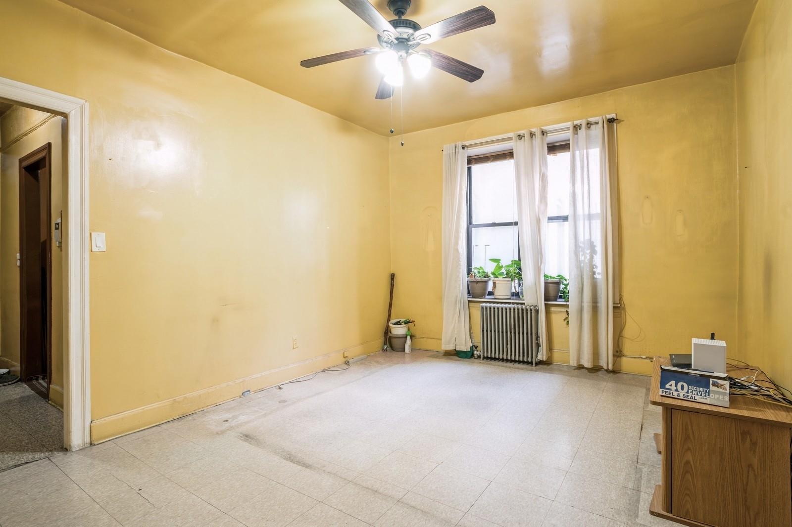 Empty room with ceiling fan and radiator heating unit