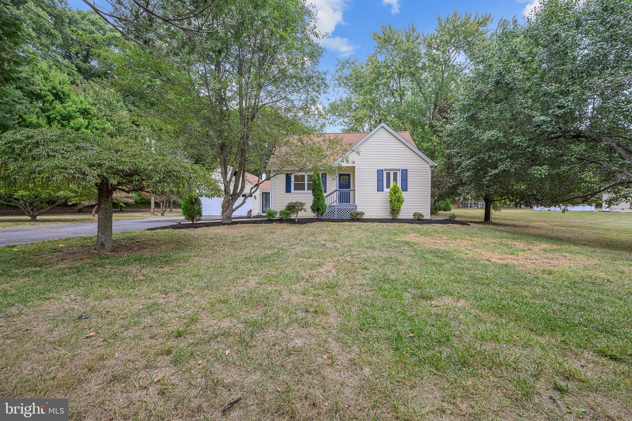 a view of a house with a yard and large trees