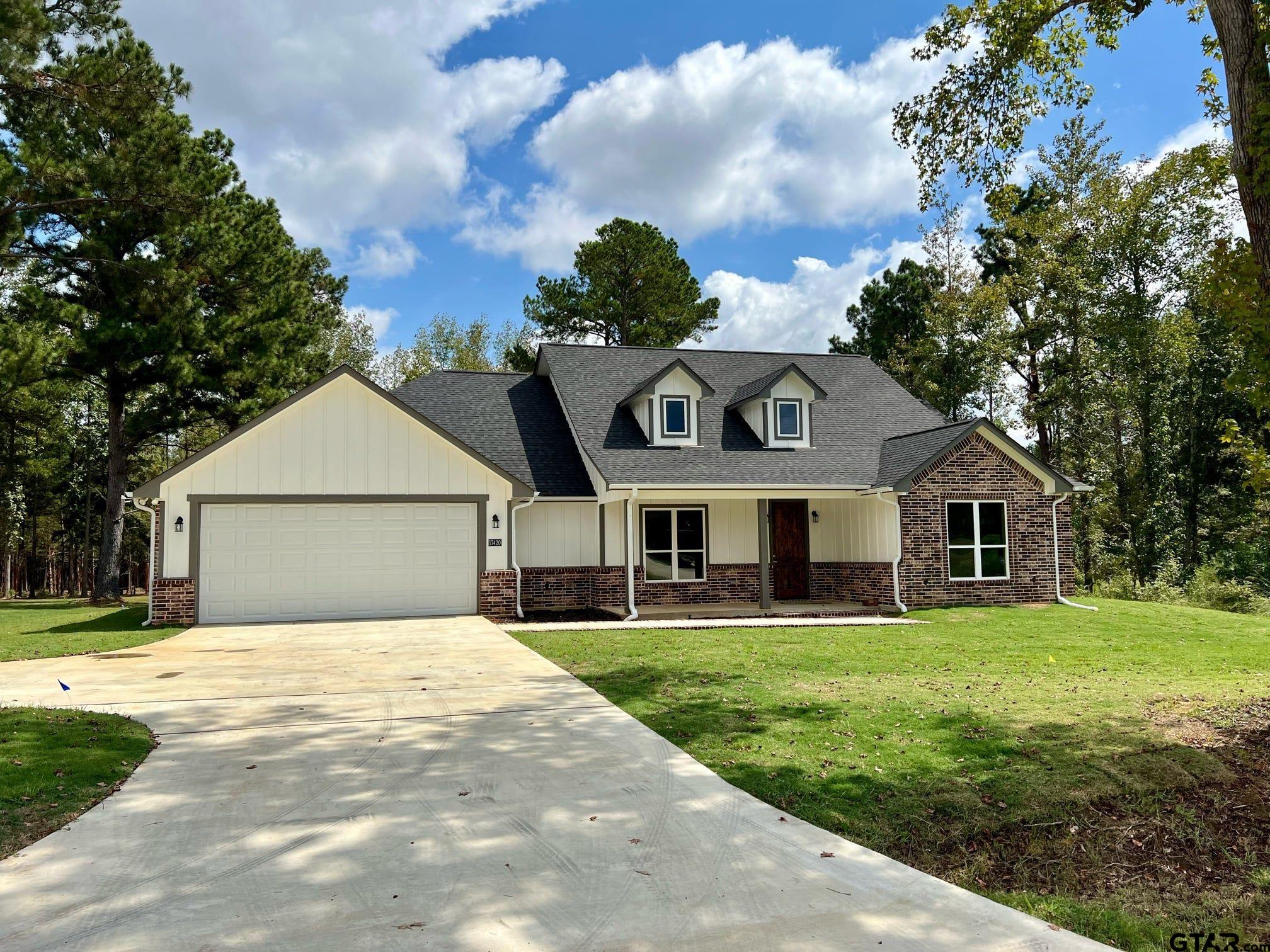 a front view of a house with a garden and trees