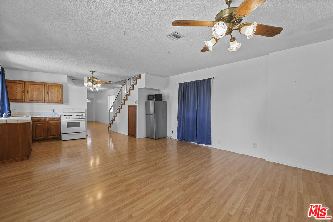 a view of a livingroom with a kitchen island wooden floor and a ceiling fan