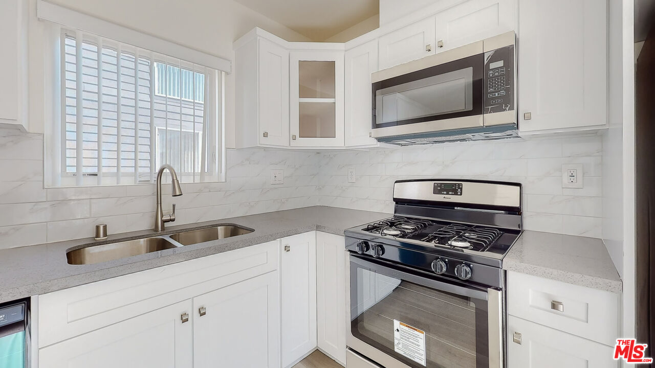 a kitchen with stainless steel appliances a stove a microwave and sink