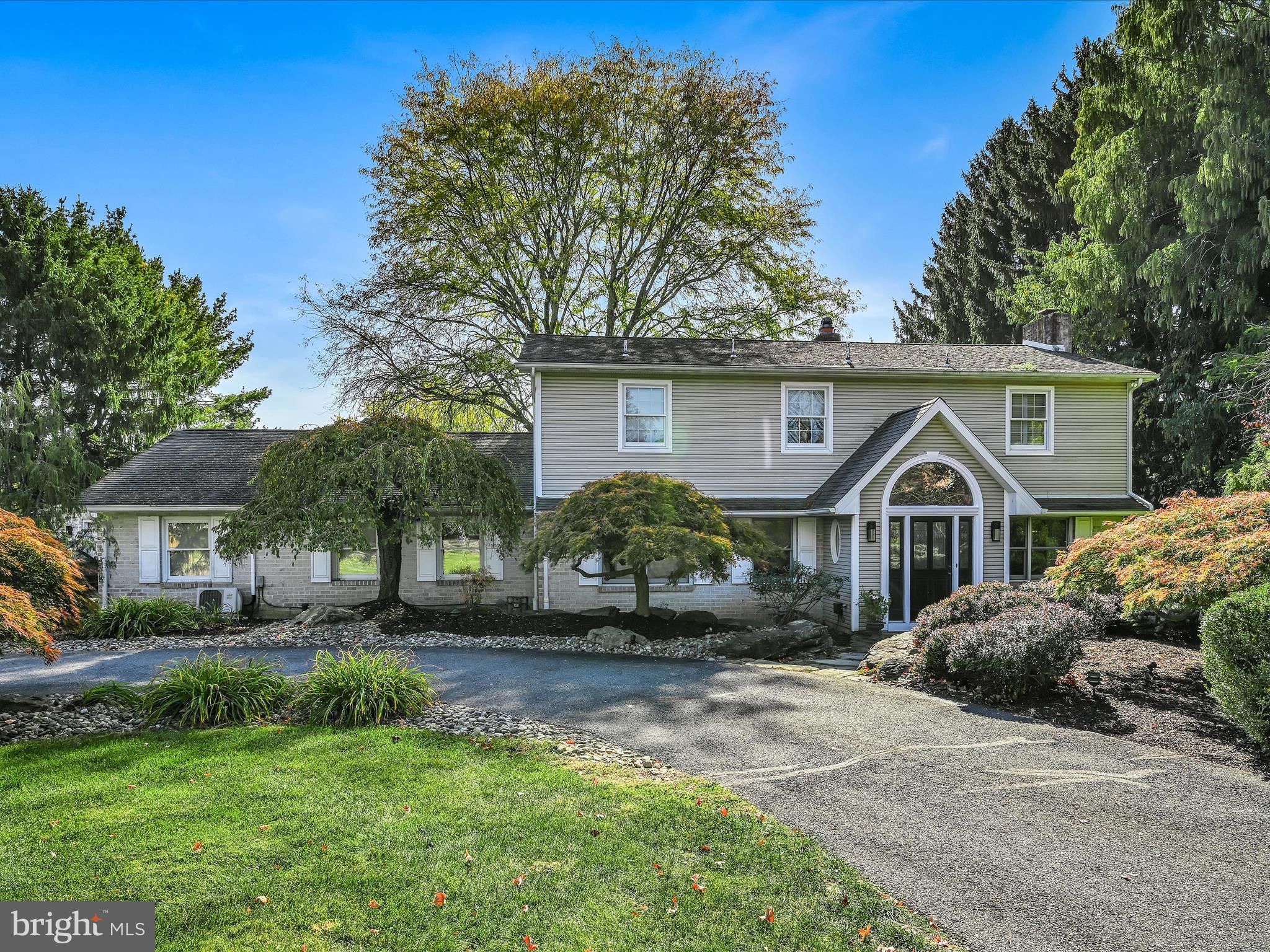 a front view of a house with a garden and trees