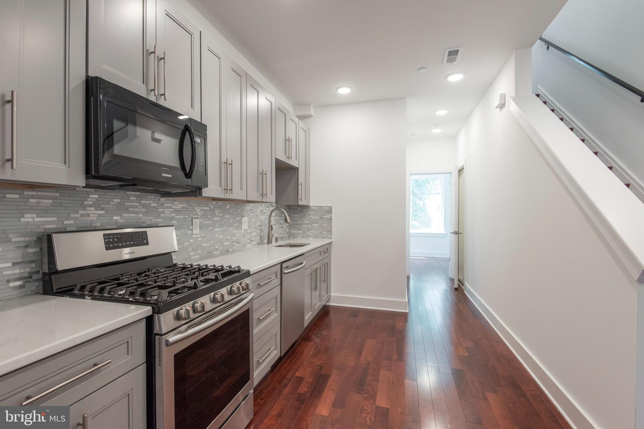 a kitchen with stainless steel appliances kitchen island granite countertop a stove a sink and a microwave