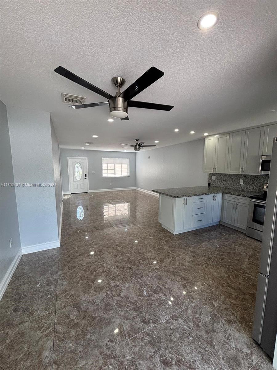 a view of a big room with wooden floor and a kitchen