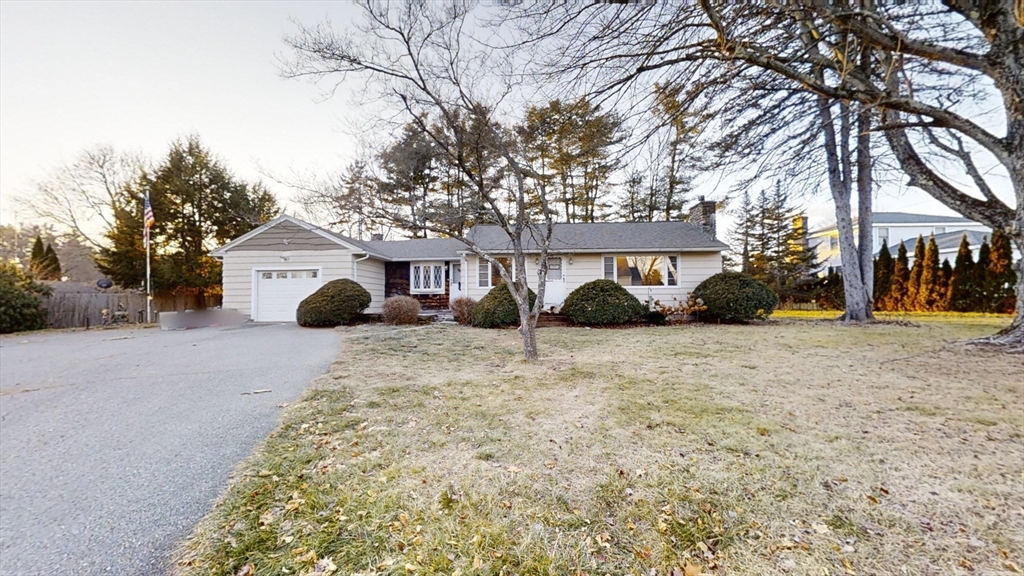 a view of a white house with a yard covered in the road