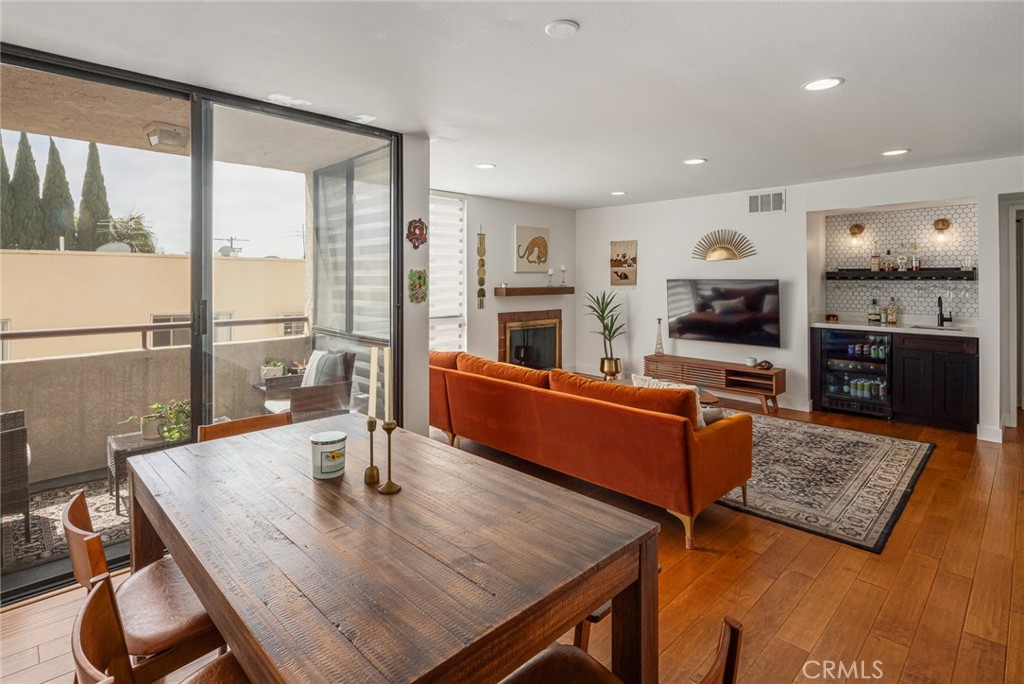 a living room with stainless steel appliances furniture wooden floor and a large window