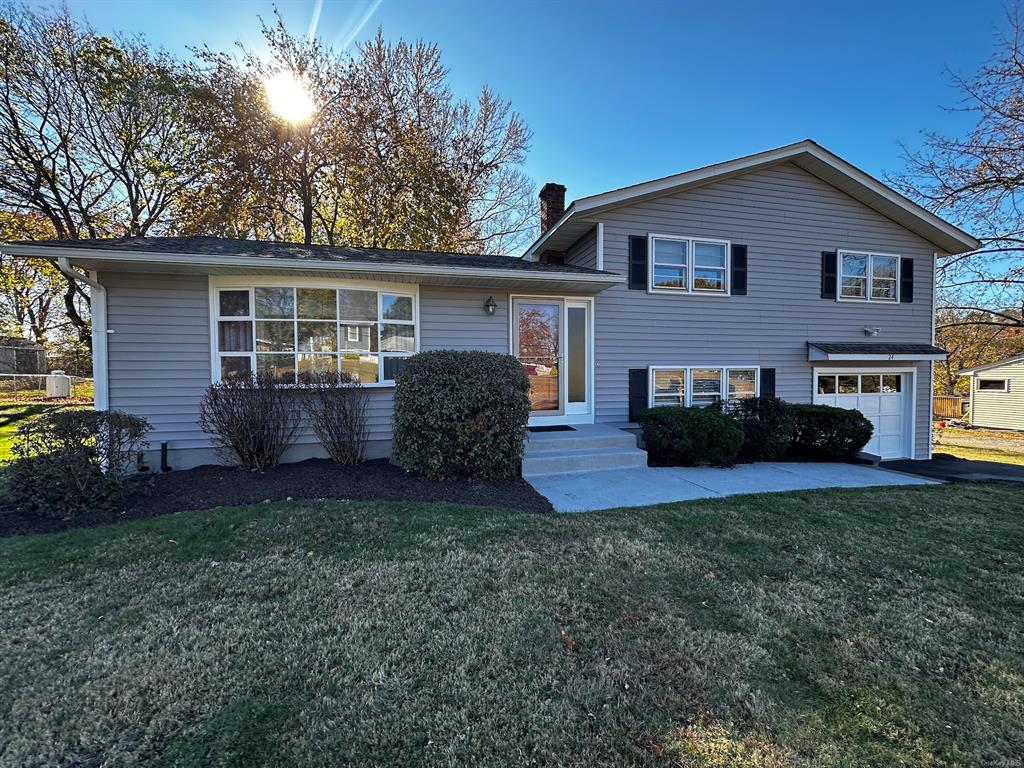 Tri-level home featuring a garage and a front yard