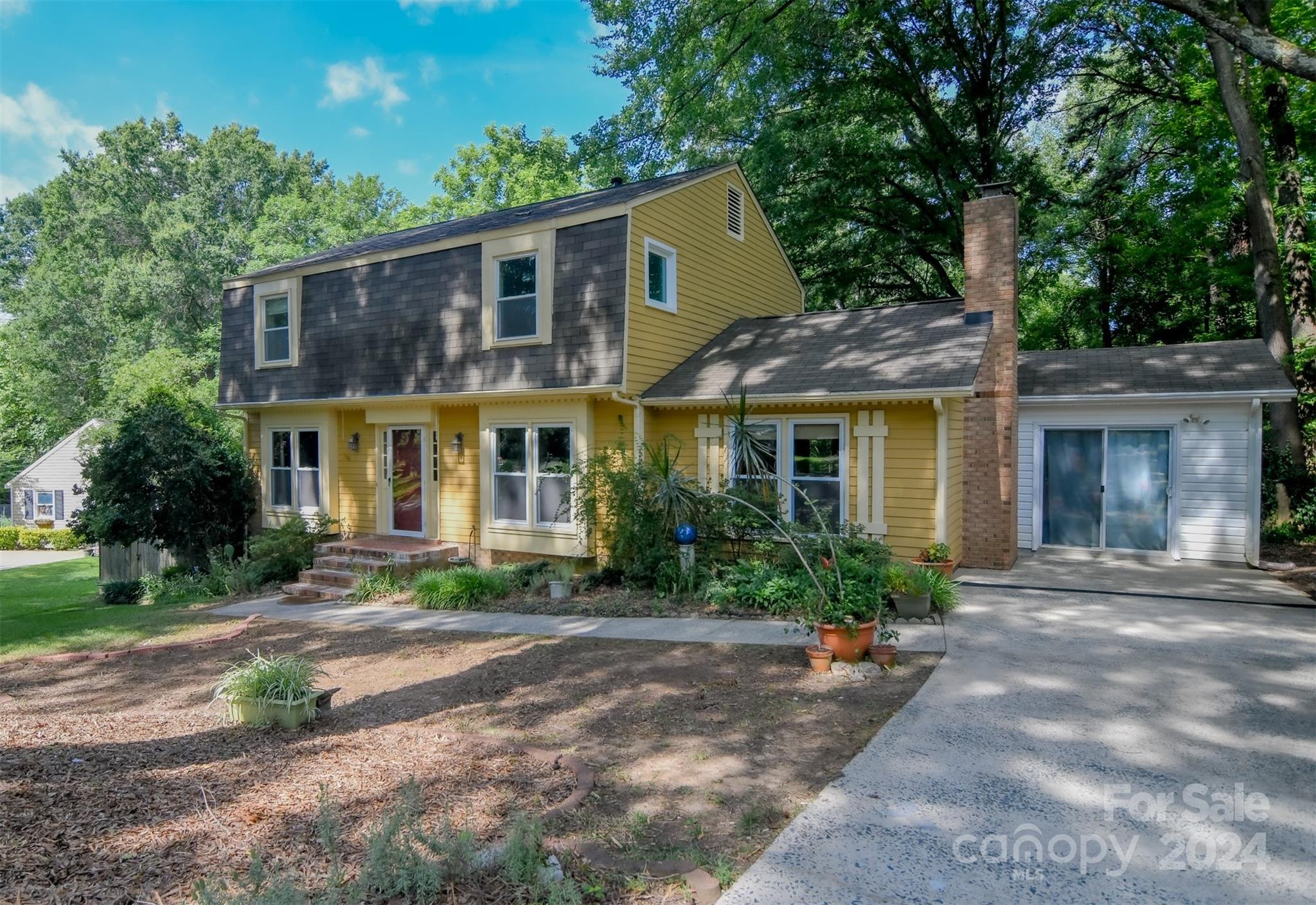 a front view of a house with garden and lots of trees