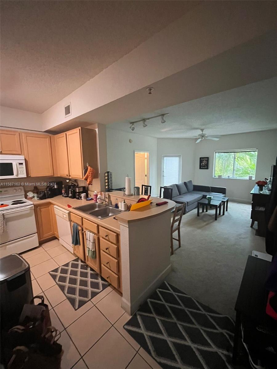 a large kitchen with lots of counter top space a sink a stove and white cabinets